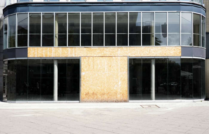 vacant commercial real estate with modern glass storefront boarded up after business closure